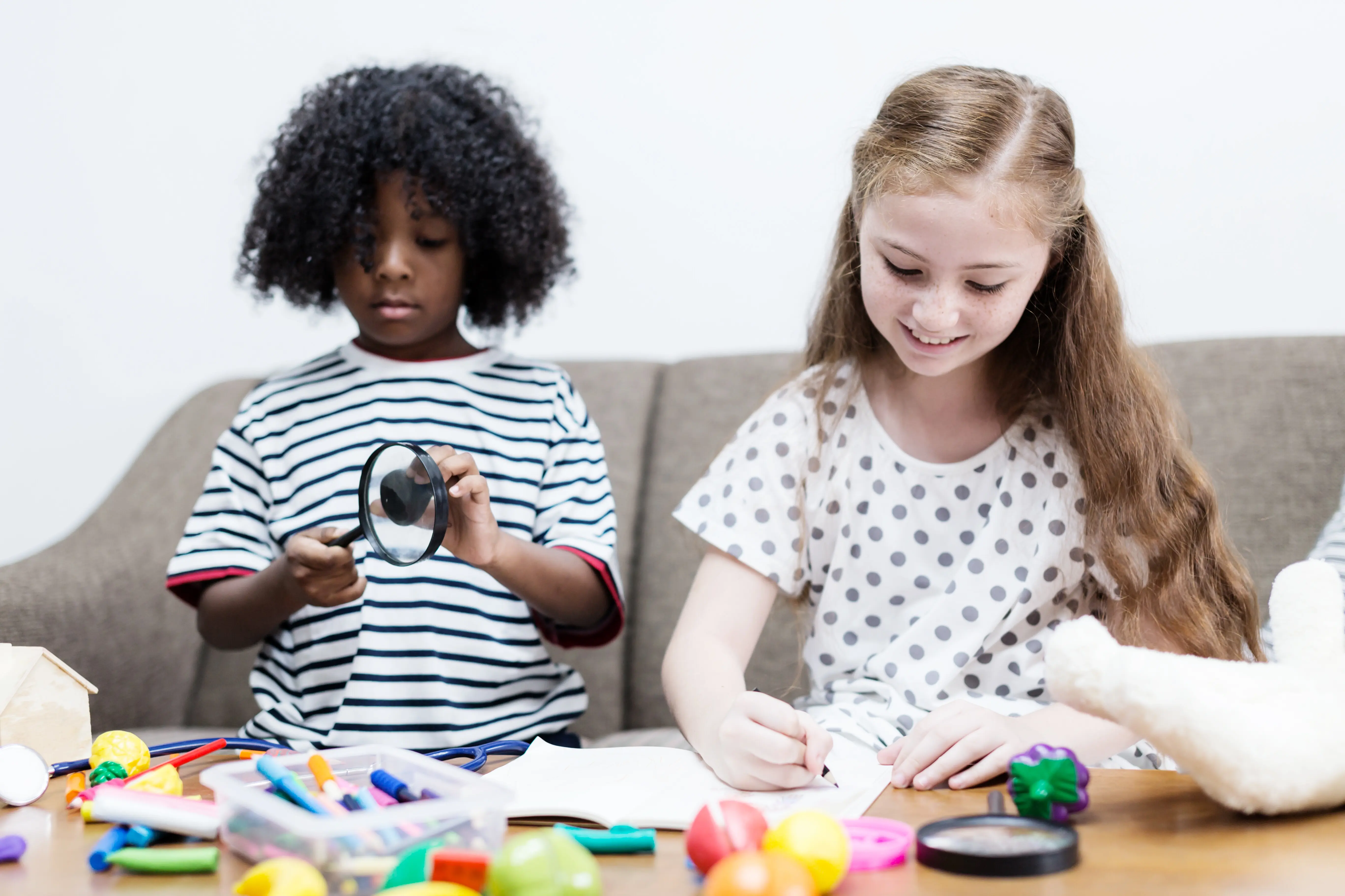 Glückliches Mädchen lächelt mit buntem Spielzeugball auf dem Sofa.